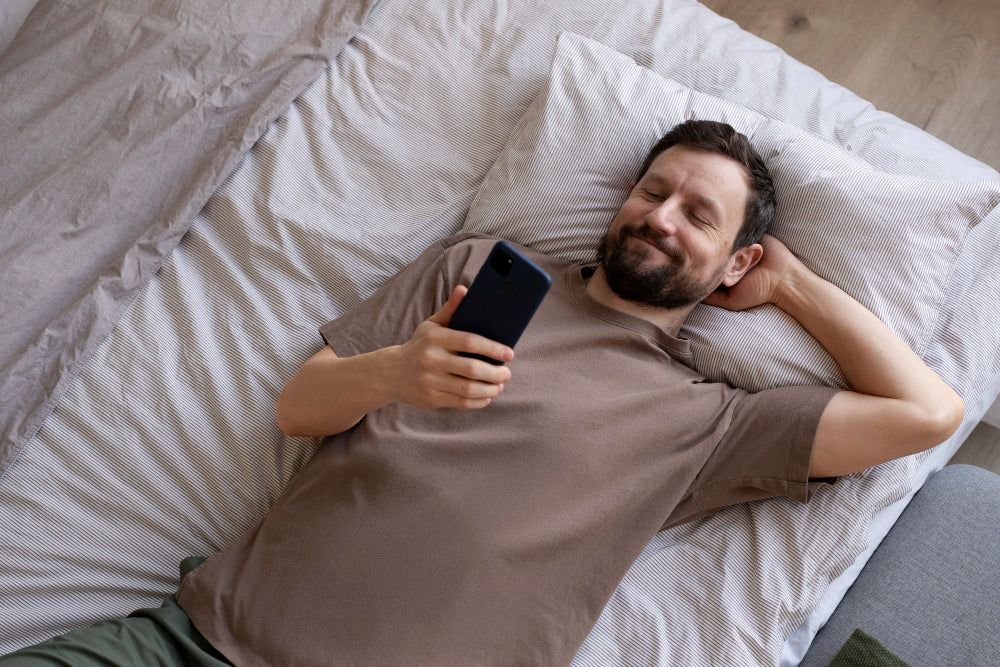 Man in bed glimlacht naar telefoon