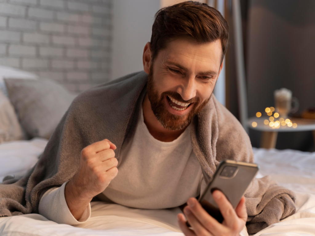 Man glimlacht naar telefoon met gebalde vuist